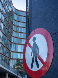 Do not walk road crossing warning sign. circular signboard attached to a vertical side wall.