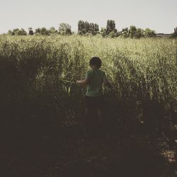 Boy standing on tree against sky