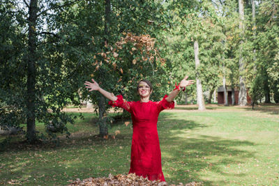 Woman with arms raised standing by plants