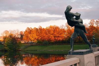 Statue by trees against sky during autumn