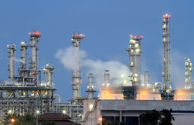 Illuminated factory against sky at night