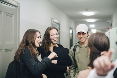 Cheerful teenage students standing in corridor