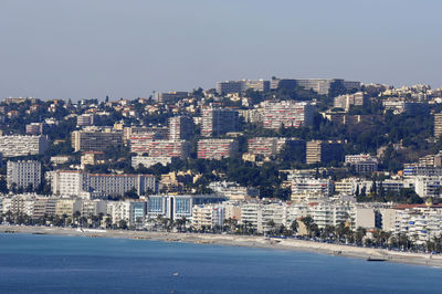 Sea by buildings against clear sky