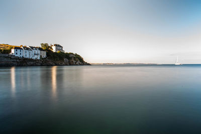 Buildings by sea against clear sky