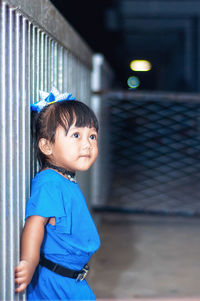 Side view of innocent girl standing by fence