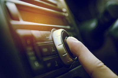 Cropped image of human finger touching music system in car