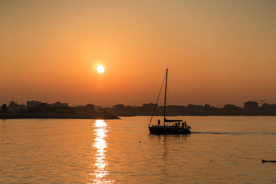 Silhouette sailboats in sea against sky during sunset