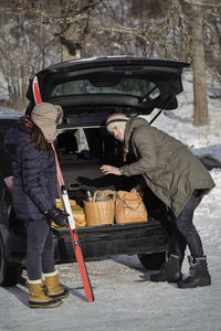 Young man communicating with woman while loading car trunk