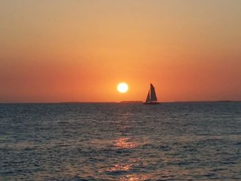 Sailboat sailing on sea against sky during sunset