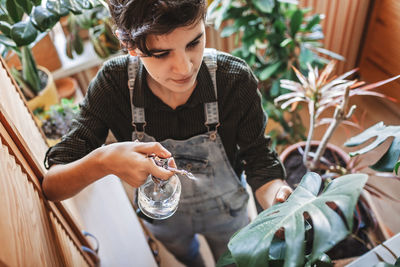 Young girl watering home plants on the balcony, green environment in room, home gardening