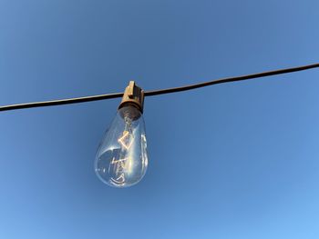 Low angle view of light bulb against blue sky