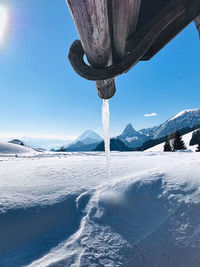 Icicles on snow covered land against sky