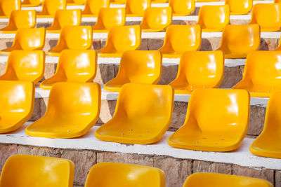 Stone steps with yellow plastic seats. empty stools without people.  absence of audience.