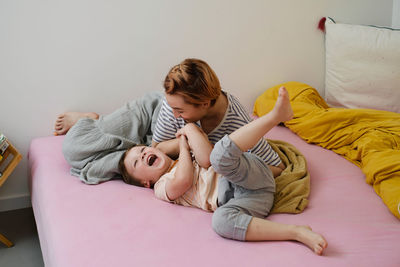 Mother having fun with son on bed. mom and toddler playing, tickling a child, laughing in the