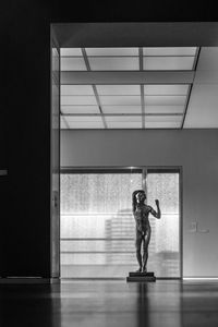 Side view of man standing by window on floor in building