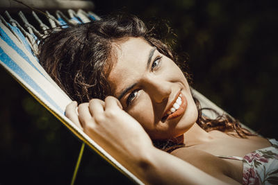 Close-up portrait of smiling young woman lying on hammock
