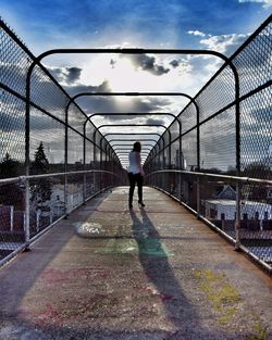 Woman walking on bridge against sky