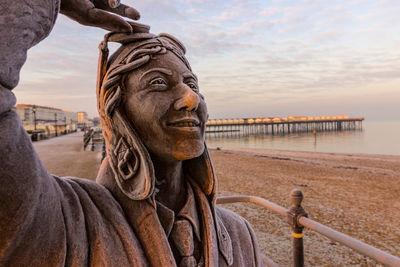 Portrait of statue by sea against sky during sunset