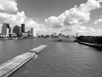 View of city at waterfront against cloudy sky