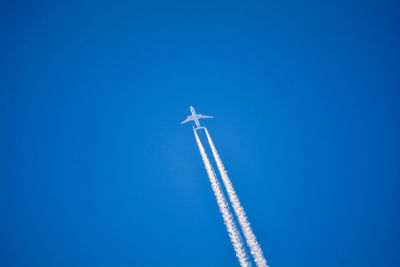 Low angle view of airplane flying against clear blue sky