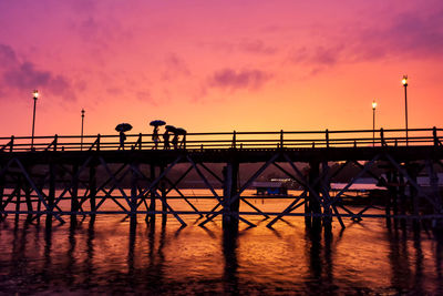 Silhouette people on pier against sky during sunset