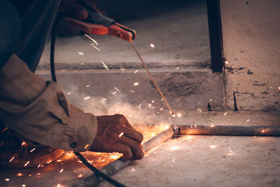 Cropped image of worker welding rods in factory