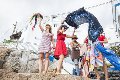 Female friends holding scarves against building