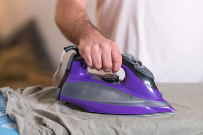 Midsection of man ironing shirt on board