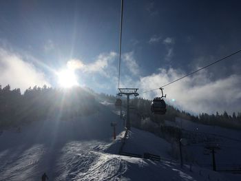 Ski lift over snowcapped mountains against sky on sunny day