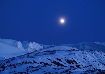 Scenic view of snow covered mountains against clear blue sky