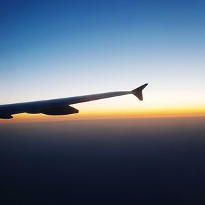 Airplane flying in sky at sunset