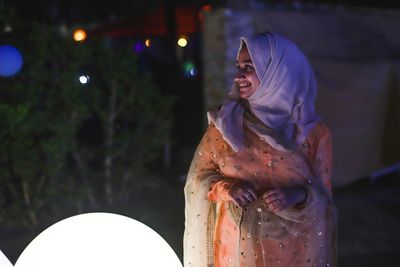 Woman looking at illuminated camera at night