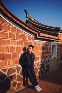 Full length of man standing against building wall