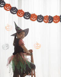 Full length of smiling woman standing against wall during halloween