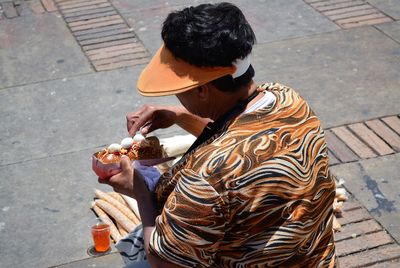 High angle view of man eating hot dog on footpath