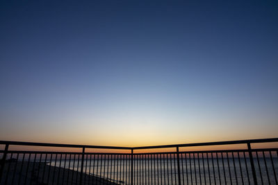 Silhouette bridge against clear sky during sunset