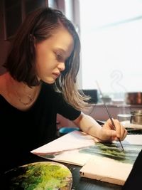Close-up of a young woman looking down while sitting on table