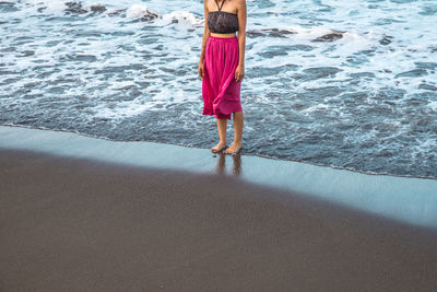 Low section of man standing on beach