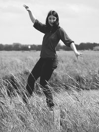 Portrait of smiling young woman jumping on field