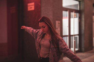 Young woman with arms outstretched against red wall