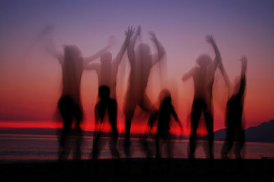 Digital composite image of silhouette people standing against sky during sunset