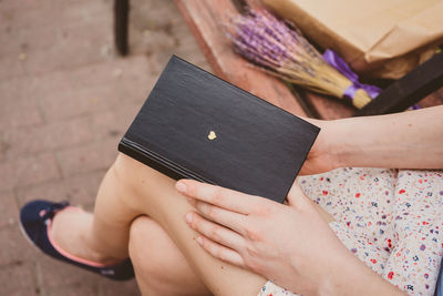 Low section of woman sitting on book