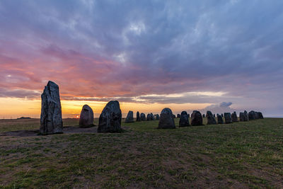 Panoramic shot of rocks on field against sky during sunset