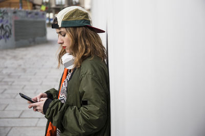 Young woman using mobile phone while standing on camera