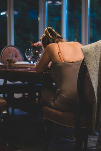 Rear view of woman sitting on table