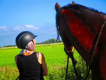 Rear view of woman standing by horse on land