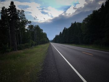 Empty road amidst trees against sky