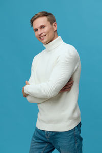 Portrait of young man standing against blue background