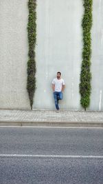 Man standing on road against wall