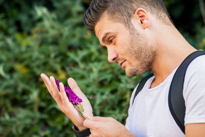 Close-up portrait of young man holding purple flower